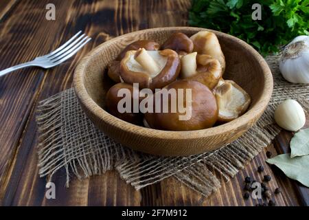 Shiitake di funghi marinati nel piatto marrone sul rustico sfondo di legno Foto Stock