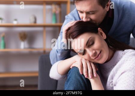 Uomo baciando la testa della donna con gli occhi chiusi Foto Stock