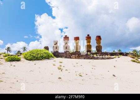 Vista posteriore delle teste di moai restaurati con nodi rossi di scoria (pukao) su AHU Nao-Nao, Anakena Beach sulla costa nord dell'isola di Pasqua (Rapa Nui) Foto Stock