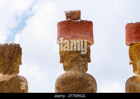 Vista posteriore delle teste di moai restaurati con nodi rossi di scoria (pukao) su AHU Nao-Nao, Anakena Beach sulla costa nord dell'isola di Pasqua (Rapa Nui) Foto Stock