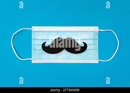 felice biglietto d'auguri giorno del padre e maschera protettiva del viso con baffi su sfondo blu, concept papà giorno in quarantena Foto Stock