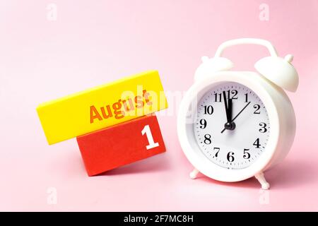 1 agosto . Giorno 1 del mese, data del calendario. Sveglia bianca su sfondo rosa pastello. Mese d'estate, giorno dell'anno concetto Foto Stock