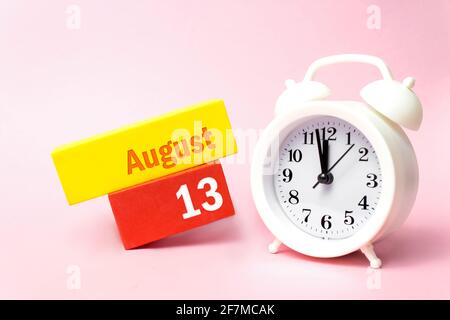 13 agosto. Giorno 13 del mese, data del calendario. Sveglia bianca su sfondo rosa pastello. Mese d'estate, giorno dell'anno concetto Foto Stock