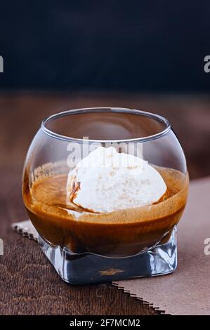 Bicchiere di espresso aromatico con porzione di dessert gelato macro su tavola di legno marrone macro shot Foto Stock