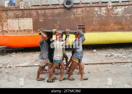 Keraniganj, Dhaka, Bangladesh. 8 Apr 2021. I lavoratori trasportano un pesante pezzo di lamiera in un cantiere navale sulla riva del fiume Buriganga, a Keraniganj, vicino a Dhaka, Bangladesh, 8 aprile; 2021. Con un numero crescente di ordini da parte di acquirenti locali e globali, l'industria cantieristica del Bangladesh sta prosperando rapidamente, contribuendo alla diversificazione del paniere di esportazione del paese e generando opportunità di lavoro. Credit: Suvra Kanti Das/ZUMA Wire/Alamy Live News Foto Stock