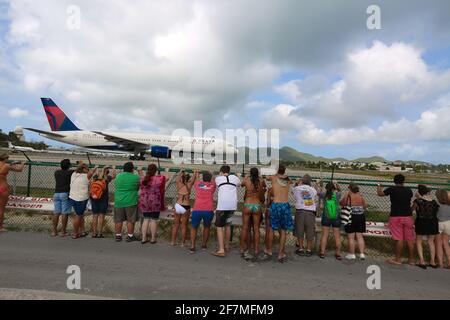 Delta volo pronto per decollo, turisti che ricevono jet blast a Maho Beach dalla partenza aereo da St. Maarten Airport nei Caraibi. Popolare t Foto Stock