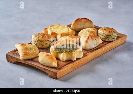Pasticceria, fatayer o samosa, manaqeesh con zaatar e formaggio. Dolci assortiti con spinaci e patate su tavola di legno Foto Stock