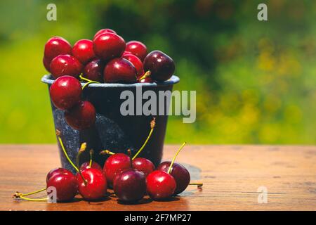 fuoco selettivo sulle ciliegie rosse dolci in una pentola con le luci verdi di bokeh della natura, stile rustico, Foto Stock