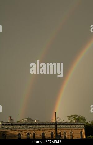 Un doppio arcobaleno su edifici di appartamenti a Brooklyn su un giornata cupa Foto Stock