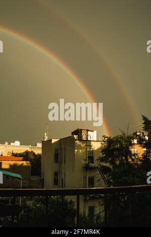 Un doppio arcobaleno su edifici di appartamenti a Brooklyn su un giornata cupa Foto Stock