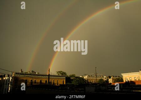 Un doppio arcobaleno su edifici di appartamenti a Brooklyn su un giornata cupa Foto Stock