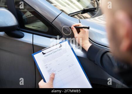 Agente assicurativo o regolatore ispettendo l'automobile dopo l'incidente Foto Stock