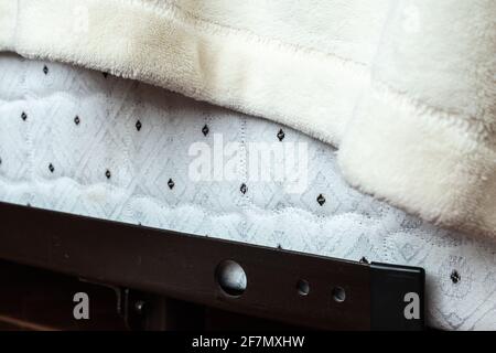 Angolo ravvicinato di una camera da letto con motivo trapuntato con puntini neri sul tessuto, coperta da una coperta bianca sfumata drappeggiato su una struttura in acciaio metallico.