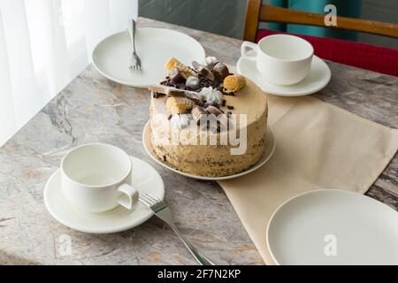 La tavola è impostata per il tè: tisane e piattini e un pan di Spagna con panna al piano di pietra Foto Stock