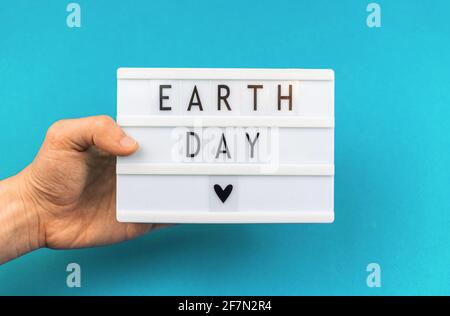 Earth Day Lettering sfondo, uomo che tiene scatola luminosa con messaggio di testo, concetto di protezione dell'ambiente Foto Stock