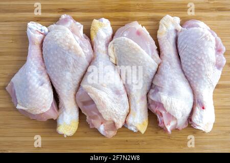 Cosce fresche di bastone di pollo crudo sul tagliere della cucina Foto Stock