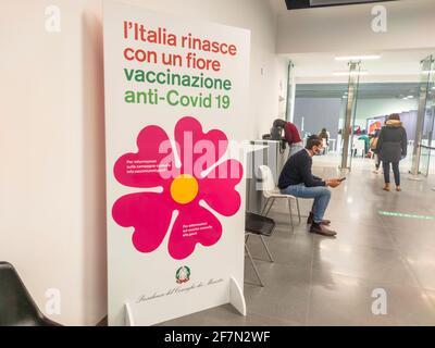 Bologna, Italia - Aprile 2021: Persone con maschere chirurgiche in coda all'interno del centro di vaccinazione italiano per vaccinarsi con il nuovo vaccino Foto Stock