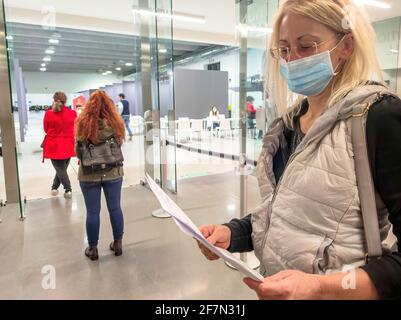 Bologna, Italia - Aprile 2021: Coda di donne con maschere chirurgiche nel centro di vaccinazione italiano per la vaccinazione europea COVID-19 Foto Stock