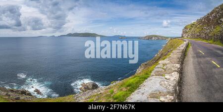 Grande panorama con strada stretta e tortuosa sul bordo della scogliera con arcipelago di piccole isole nella penisola di Dingle, Wild Atlantic Way, Kerry, Irlanda Foto Stock