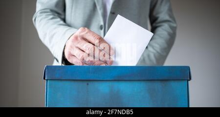 mano maschile che mette il voto in scrutinio Foto Stock