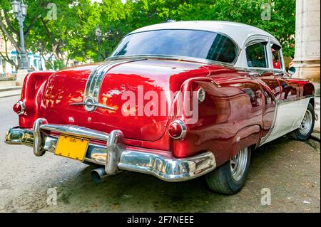 Una vista posteriore di un Pontiac vintage del 1950 rosso e bianco con targa Cuba parcheggiata su una strada della città, l'Avana, Cuba. Foto Stock