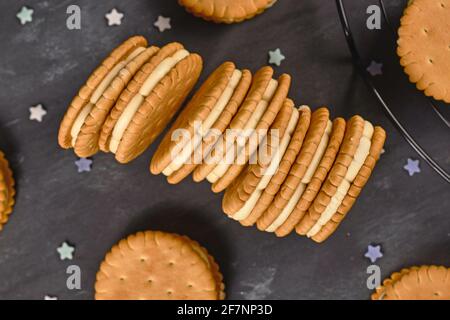 Biscotti sandwich riempiti di panna con spruzzi su sfondo scuro Foto Stock
