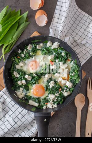 Shakshuka verde. Uova fritte con aglio selvatico e formaggio feta Foto Stock