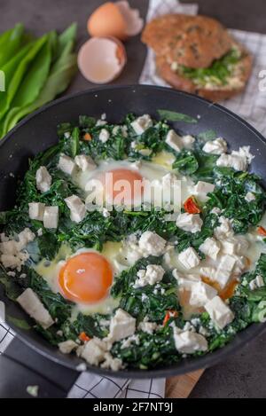 Shakshuka verde. Uova fritte con aglio selvatico e formaggio feta Foto Stock