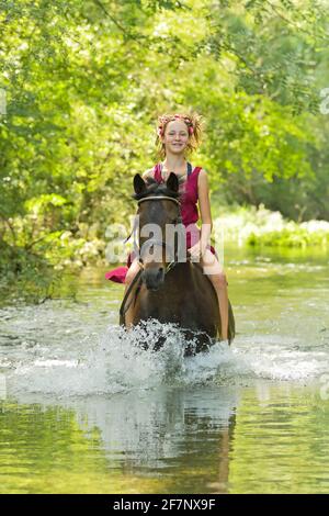 Ragazza sul dorso di un pony tedesco che cavalca bareback in un streaming Foto Stock