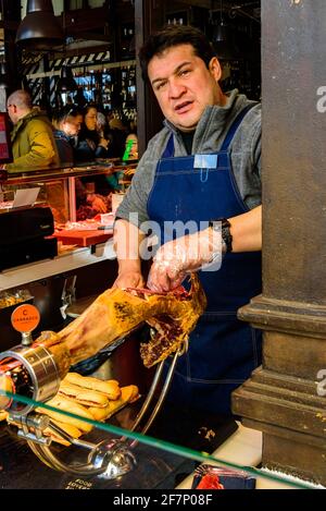 Madrid, Spagna – 11 gennaio 2020: Al Mercado de San Miguel Market (un bel mercato gastronomico), un venditore è pronto a vendere il suo prosciutto iberico. Foto Stock