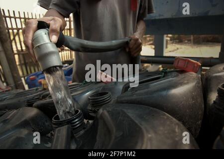 Un itinerante d'acqua che riempie le lattine di jerry con acqua ad una stazione d'acqua a Jakarta, Indonesia. L’uso globale di acqua dolce è aumentato di un fattore di sei negli ultimi 100 anni e continua a crescere ad un tasso di circa il 1% all’anno dal 1980s, secondo una recente pubblicazione delle Nazioni Unite sull’acqua. "l'unità centrale di questa crescita può essere attribuita a una combinazione di crescita demografica, sviluppo economico e modelli di consumo in evoluzione", afferma la relazione. © Reynold Sumayku Foto Stock