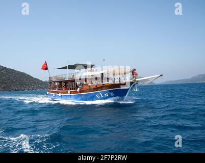 Demre, Turchia - 07.07.2020. Yacht da diporto in mare. Nave turistica con persone a bordo con bandiera turca vela sulle onde. Escursioni in rapido movimento s Foto Stock