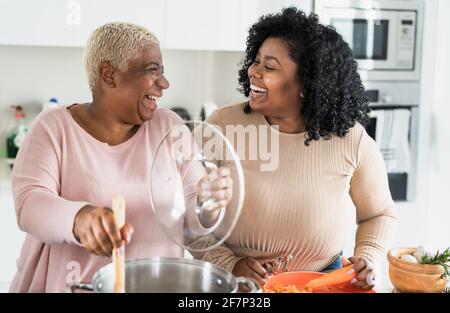 Felice madre e figlia afro che preparano il pranzo insieme in moderno Casa cucina - cibo e genitori concetto di unità Foto Stock