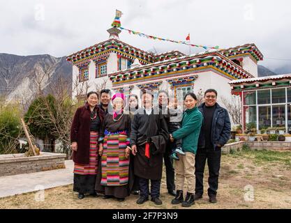 (210409) -- LHASA, 9 aprile 2021 (Xinhua) -- Ngawang Nyima (C) propone una foto di gruppo con i suoi familiari di fronte alla sua residenza nella città di Qamdo, regione autonoma del Tibet della Cina sudoccidentale, 18 febbraio 2021. Ngawang Nyima, 84 anni, è nato a Naixi Township, nella contea di Mangkam, nella città di Qamdo, nella regione autonoma del Tibet della Cina sudoccidentale, ed era un serf. Carico di pesanti tasse, iniziò a gregge di pecore per i padroni di casa quando non aveva più di otto anni, e fu costretto a prelevare il bittero da una salina del fiume Lancang. Il sentiero per la saliera era così precipitoso che un singolo passo incauto sarebbe stato Foto Stock