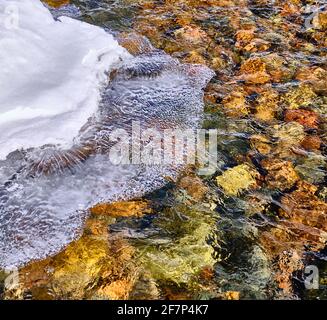 Concetto di bellezza e grandezza della natura: Spettacolare struttura del bordo di ghiaccio che sovrasta l'acqua del fiume di montagna Foto Stock