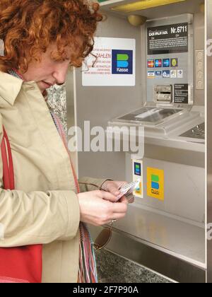 Donna dai capelli rossi alla banca automa, Austria Foto Stock