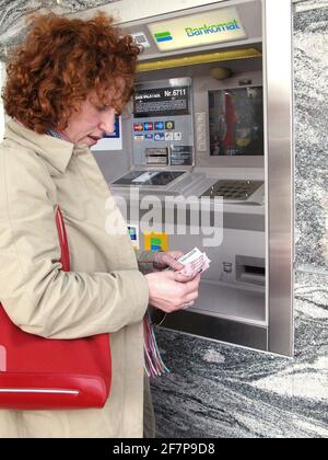 Donna dai capelli rossi alla banca automa, Austria Foto Stock