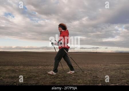 Donna che fa nordic walking sul bordo del campo, Austria Foto Stock