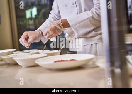 Lo chef aggiunge spezie ai piatti in molte ciotole Foto Stock