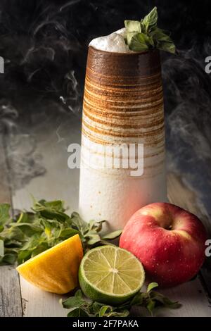 Bel cocktail fruttato, lungo e alto, preparato con lime, mela e limone freschi, servito con una guarnitura salvia e un po' di fumo Foto Stock