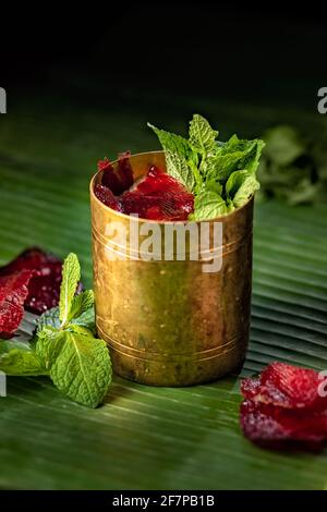 Cocktail rinfrescante con gelatina di barbabietole, menta fresca e vodka, serviti in una bella tazza d'oro Foto Stock