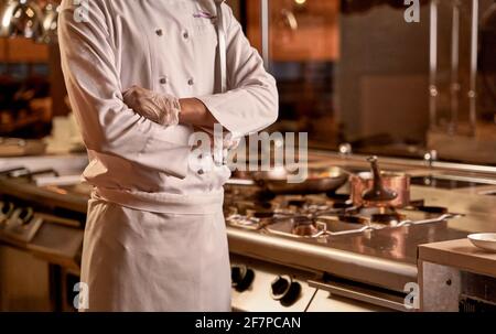Le mani di uno chef si sono piegate sullo stomaco Foto Stock