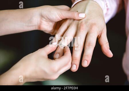 La sposa mette l'anello di nozze sul dito dello sposo. Primo piano Foto Stock