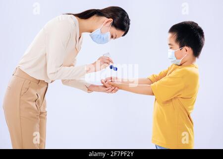 La madre insegnò al ragazzino ad usare l'igienizzatore per le mani con la mamma Foto Stock