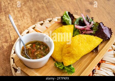 Un'empanada colombiana ripiena di maiale tirato e servita con Pico de Gallo paesaggio Foto Stock