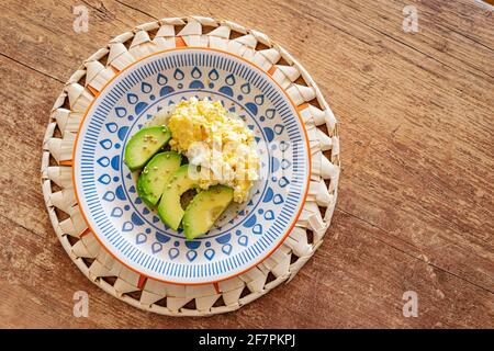 Un piatto di uova strapazzate servito insieme a fette di fresco avocado su un pezzo di pane di farina di mais Foto Stock