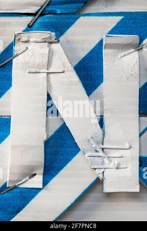 Pinzate insieme con la lettera bianca N su un blu e un bianco sfondo a strisce Foto Stock