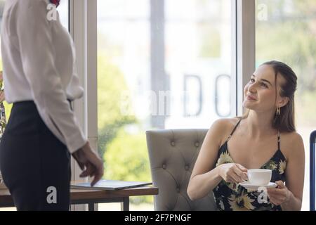 donna turistica che va a riempire e firmare il modulo di registrazione del check-in dell'hotel al banco della reception, kundenservice quando arrivo destinazione per la vacanza estiva Foto Stock