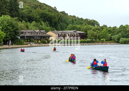 Persone in kayak verso l'hotel Lodge on Loch Lomond nel Loch Lomond e Trossachs National Park, Luss, Scozia, Regno Unito Foto Stock