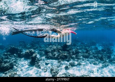 Donna con pinne che nuotano nell'oceano blu. Foto Stock